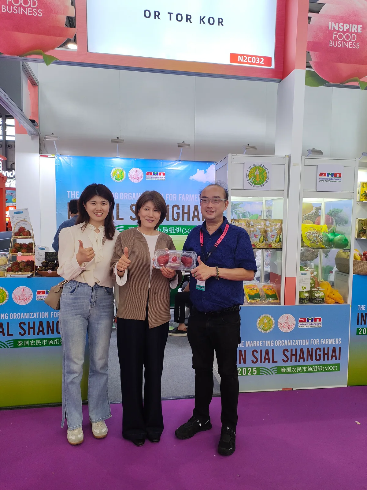 Three people discussing fruit packaging at an exhibition booth