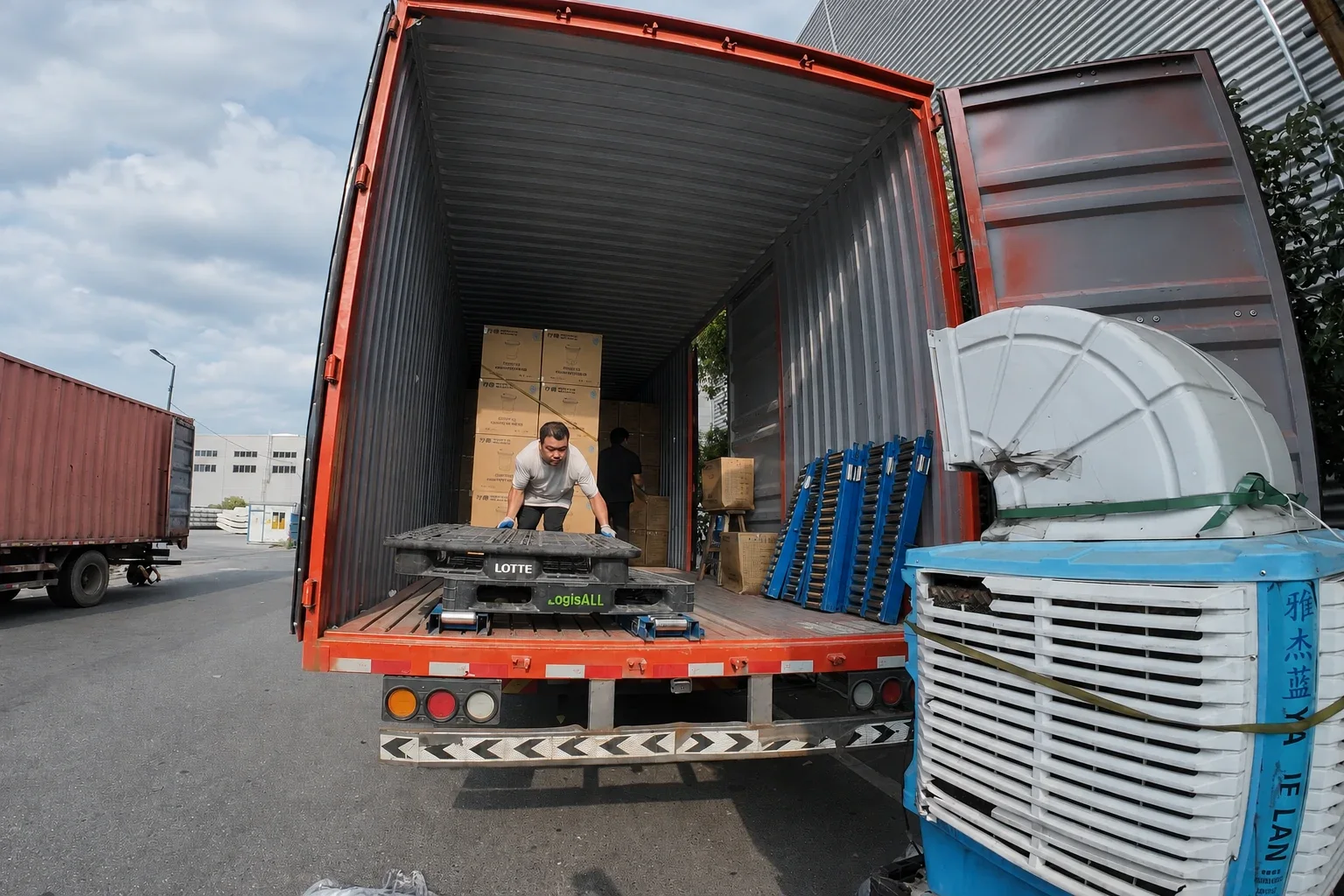 Workers arranging packed cartons inside a shipping container