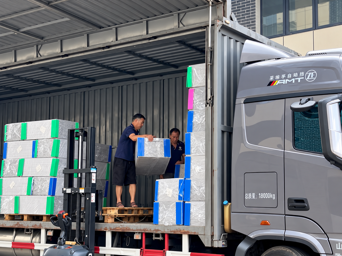 Workers loading wrapped bundles into a truck