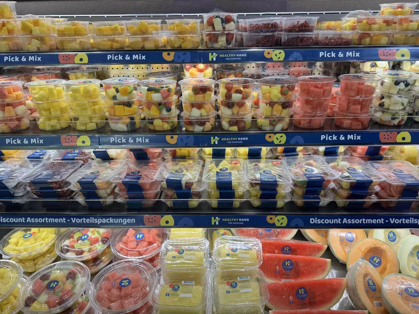 A California supermarket uses fruit cups, clamshells, trays, labels, and wraps for different sale units and retail positions.